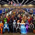 High definition image of an exciting lineup of people who are dressed up as various pop culture icons at the 2024 Arkansas Pop Culture Extravaganza event. The image includes people in vibrant and detailed costumes, depicting characters from popular television shows, movies, comics, and video games. In the background, there should be different booths and stages hosting various events like comic book signings, cosplay contests, and discussion panels on various pop culture subjects. The atmosphere is lively and filled with anticipation.